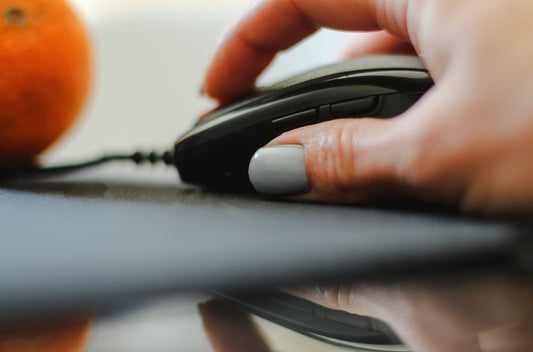 person holding black and gray corded computer mouse